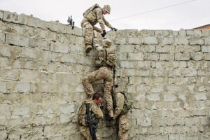 A group of Army Rangers uses teamwork to climb a wall