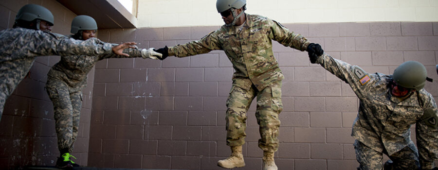 Soldiers help each other across an obstacle at Army cadre leadership training