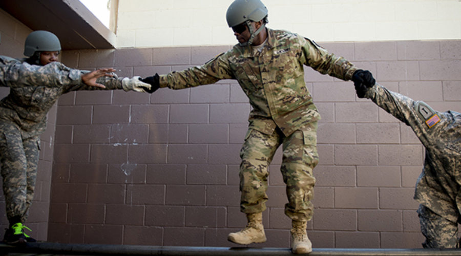 Soldiers help each other across an obstacle at Army cadre leadership training